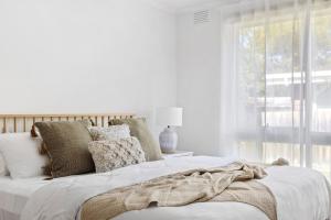 a white bedroom with a bed and a window at Bayside Retreat - Cosy Fire Beach Games Room in McCrae