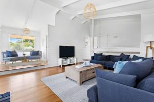 a living room with blue couches and a tv at Bayside Retreat - Cosy Fire Beach Games Room in McCrae