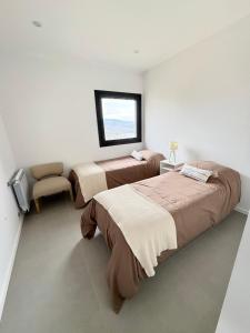two beds in a room with a window and a chair at Cantera Tempo 2 in Esquel