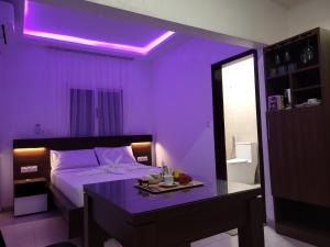 una habitación morada con una cama y una mesita. en Sheyllo Suites Abidjan - Cocody, en Abiyán
