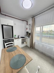 Una sala de estar con una mesa y una cocina. en DE Apartment, en Rădăuţi