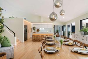a dining room with a table and chairs and a kitchen at Luxury Retreat - Spa Beach Golf Wineries in Mornington