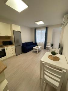 a kitchen and a living room with a blue couch at Well Equipped New Family Friendly One-Bedroom Flat in Sandanski