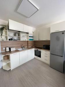 a kitchen with white cabinets and a stainless steel refrigerator at Well Equipped New Family Friendly One-Bedroom Flat in Sandanski