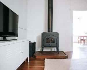 雷德山The Sunday School - Timeless Cottage Wine Region的一间带炉灶和电视的客厅