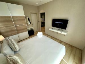 a bedroom with a large white bed and a flat screen tv at Beatiful titlhalo apartment in Nai Yang Beach