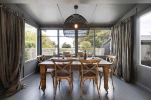 a dining room with a table and chairs and windows at Hillside Cottage - Wineries Pool in Red Hill South