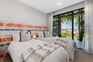 een slaapkamer met twee bedden en een groot raam bij Martha's Retreat - Waterfront Luxury in Safety Beach +27 foto's