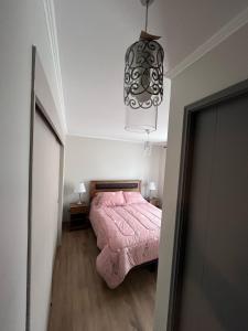 a bedroom with a pink bed and a chandelier at Cómoda casa nueva 3 D 2 B in La Serena