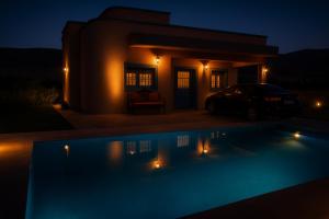 a night view of a swimming pool in front of a house at Tazouta Farm Villa with Private Pool & Mountain Views in Tazouta