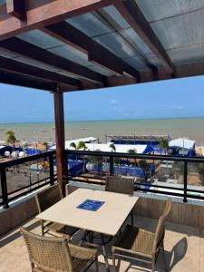 a table and chairs on a balcony with a view of the beach at Suite vista mar marinas cabo branco in João Pessoa