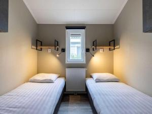 two beds in a room with a window at Karper Vakantiepark De Groote Vliet in Wervershoof