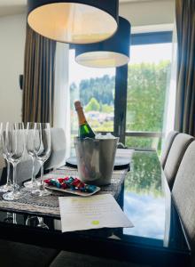a table with a bottle of wine and glasses on it at Village Lake Luxury Apartments in Hanmer Springs
