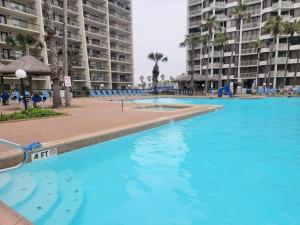a large swimming pool with blue water in front of buildings at Beachfront Resort with Heated Pool Saida Royale 9039 in South Padre Island