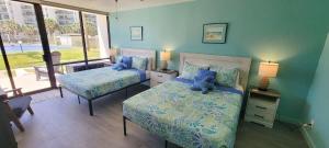 two beds in a bedroom with blue walls and windows at Saida Royale 9018 condo in South Padre Island