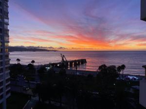 a view of the ocean and a pier at sunset at Habitación frente a Muelle Vergara en un departamento in Viña del Mar +1 photo