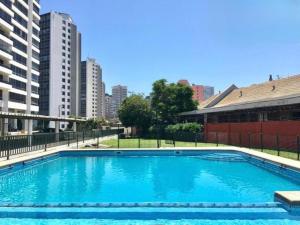 a large blue swimming pool in front of some buildings at Habitación frente a Muelle Vergara en un departamento in Viña del Mar