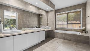 a bathroom with two sinks and a tub and a window at Que Syrah in Pokolbin
