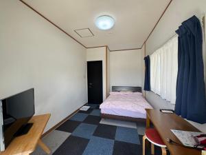 a bedroom with a bed and a desk and a television at ジンジャー in Miyako-jima