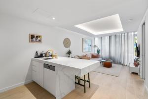 a white kitchen with a large white counter top at Grand Prix Elite Apartment in Melbourne