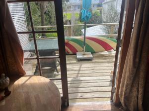 an open door to a patio with a surfboard on a deck at The Windsor Suite in New Plymouth
