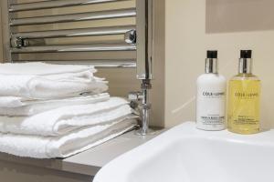 a bathroom sink with towels and a bottle of soap at Stanley Lodge Farmhouse in Cockerham +15 photos