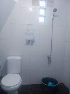 a white bathroom with a toilet and a shower at villa omah citeko 2 in Tagalbato