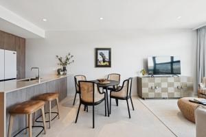 コフスハーバーにある1106 at CODA - Style and Luxury in the Heart of Coffsのテーブルと椅子のあるキッチンとリビングルーム