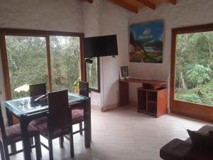 a living room with a table and chairs and windows at Cabaña campestre in Medellín