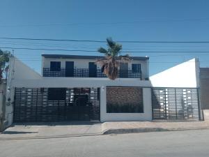 a white house with a palm tree in front of it at American Consulate 5 minutes away D1 in Manuel F. Martínez