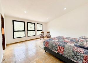 a bedroom with a bed and two chairs in it at Villa Lorena es un Lugar Magico para desconectarte in Jalatlaco