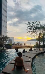 a group of people sitting around a swimming pool at The Shore Kota Kinabalu by Ems Executive Suites Seaview in Kota Kinabalu