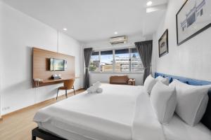 a bedroom with a large white bed and a desk at River View Residence in Bangkok