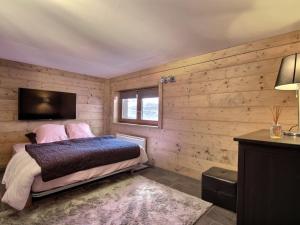 La Plagne TarentaiseにあるChalet 14 personnes, jacuzzi et garage - FR-1-455-268の木製の壁のベッドルーム1室、ベッド1台、テレビが備わります。