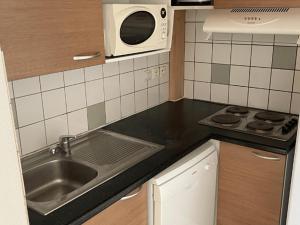 eine Küche mit Spüle und Mikrowelle in der Unterkunft Appartement avec Terrasse pour 4 personnes à Saint-Georges-d'Oléron - API-1-52-630 in Saint-Georges-dʼOléron
