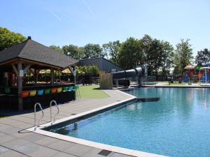 una piscina con tobogán y un parque infantil en Lakeside Chalet Retreat in Green Setting, en Lathum
