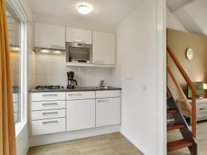 a kitchen with white cabinets and a stove top oven at Wooded Park Retreat in Drenthe in Midlaren +24 photos