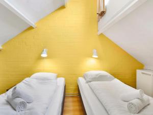 two beds in a room with a yellow wall at Wooded Park Retreat in Drenthe in Midlaren