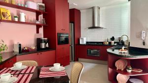 a kitchen with red cabinets and a table with chairs at Casa do Lago em Londrina in Londrina