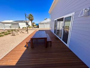 a wooden deck with a bench on the side of a house at Driftwood Beach House - Coastal Haven North Beach in Wallaroo