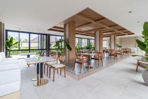 a restaurant with tables and chairs and windows at Sunshine Prestige Resort and Spa in Cha Am