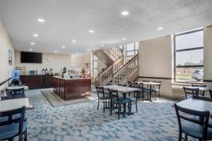 Un restaurante con mesas y sillas y una escalera. en SureStay Plus Hotel by Best Western Greenwood, en Greenwood