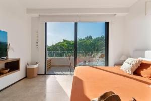 1 dormitorio con cama de color naranja y balcón en Vibra Bonito - Boho Chic Studio with Rooftop & Infinite Pool, en Tulum