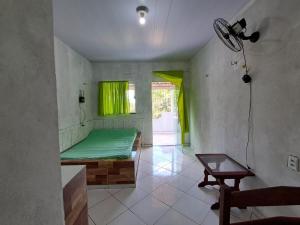 a small room with a green bed and a table at Casa Ariramba - Your place in COP30 in Belém