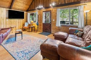 a living room with a leather couch and a television at Rainier Vintage Retreat With Hot Tub-Fireplace-WiFi in Ashford