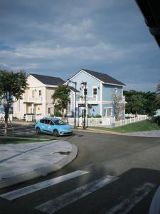a blue car driving down a street with houses at Villa ATH Novaworld Phan Thiết 3PN in Bình Tú
