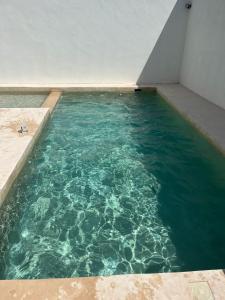 a swimming pool with blue water in a building at Descanso y confort, Casa preciosa y alberca privada in Cholul