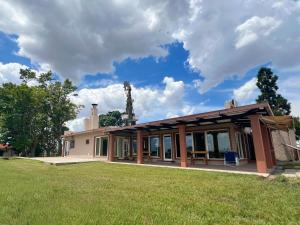 une maison avec un champ herbeux devant elle dans l'établissement Los Álamos - casa de campo, à Juan L. Lacaze