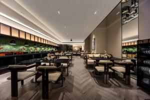 a dining room with tables and stools at Healing Mind International Hotel Guangzhou Tianhe Sports Center Linhexi Metro Station Branch - Free Deliver Service to Guangzhou Baiyun International Airport & Free Deliver Service to Canton Fair Complex During Canton Fair Period in Guangzhou