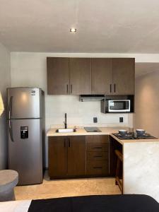 a kitchen with a stainless steel refrigerator and wooden cabinets at Studio with balcony in the downtown, WiFi 150MB, laundry and parking free in Tulum